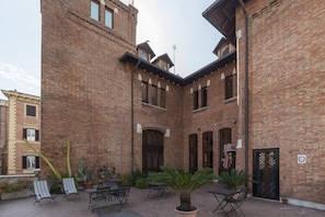 A courtyard with brick walls, outdoor seating, and potted plants.