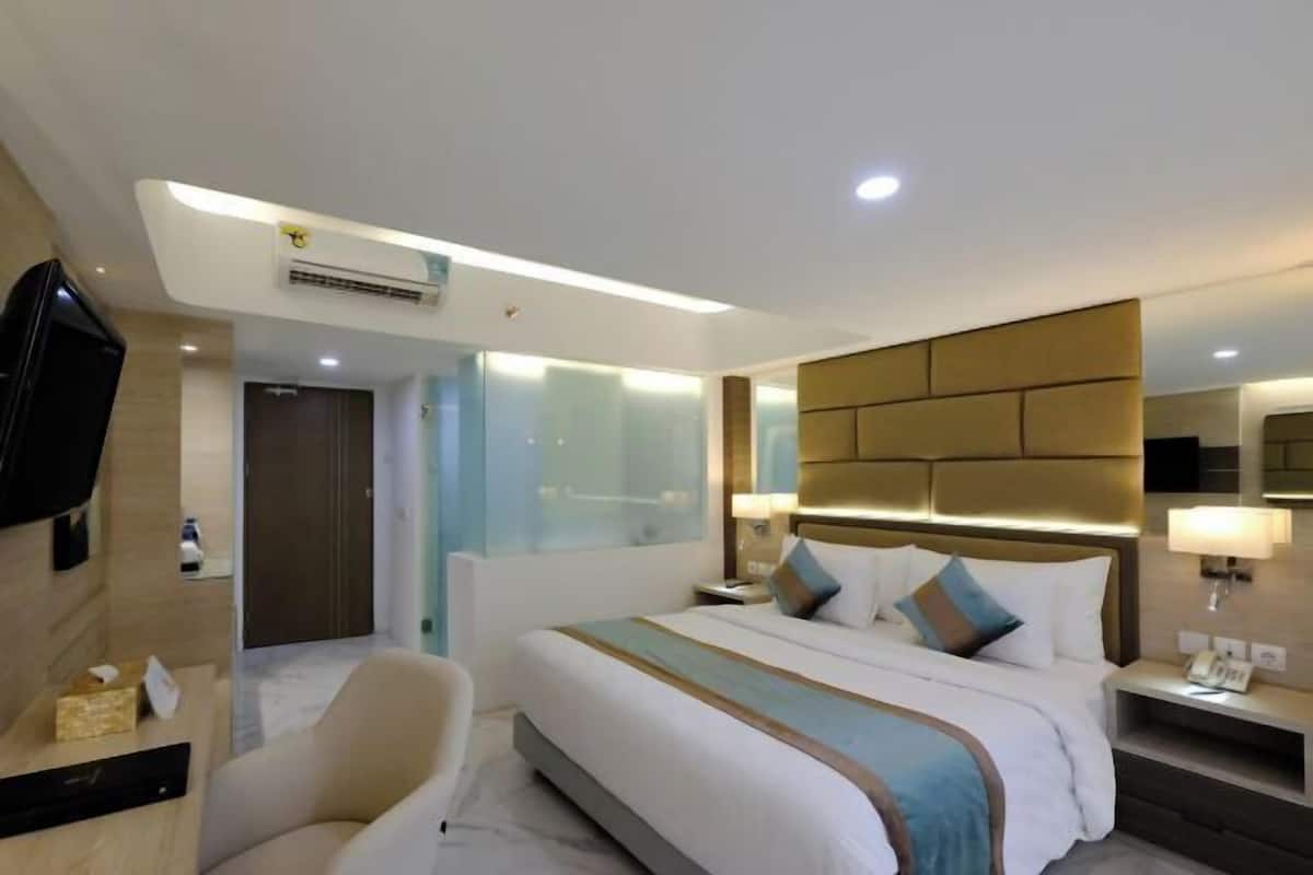 Een hotelkamer met een bed, nachtkastjes, een televisie en een airconditioning.