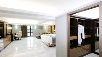 A modern hotel room with a large bed, a desk, and a walk-in closet.