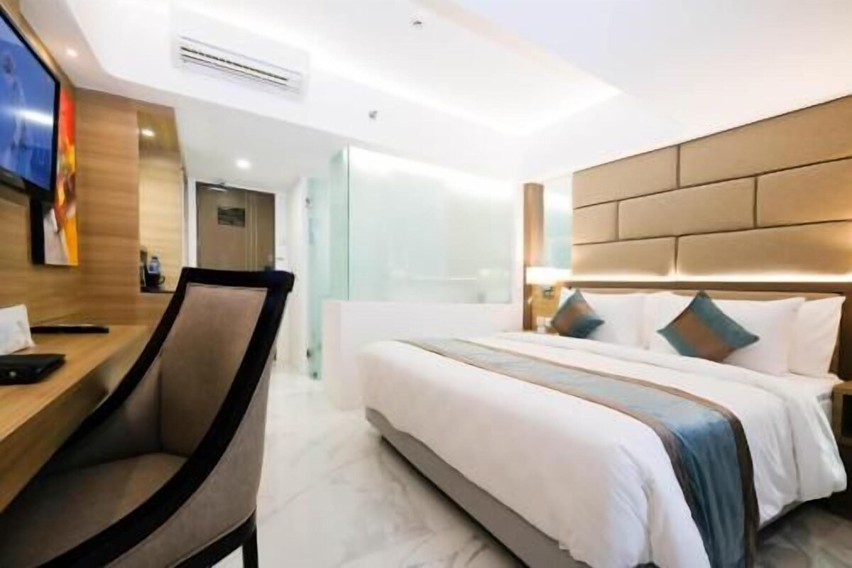 A hotel room with a bed, a desk, and a chair.