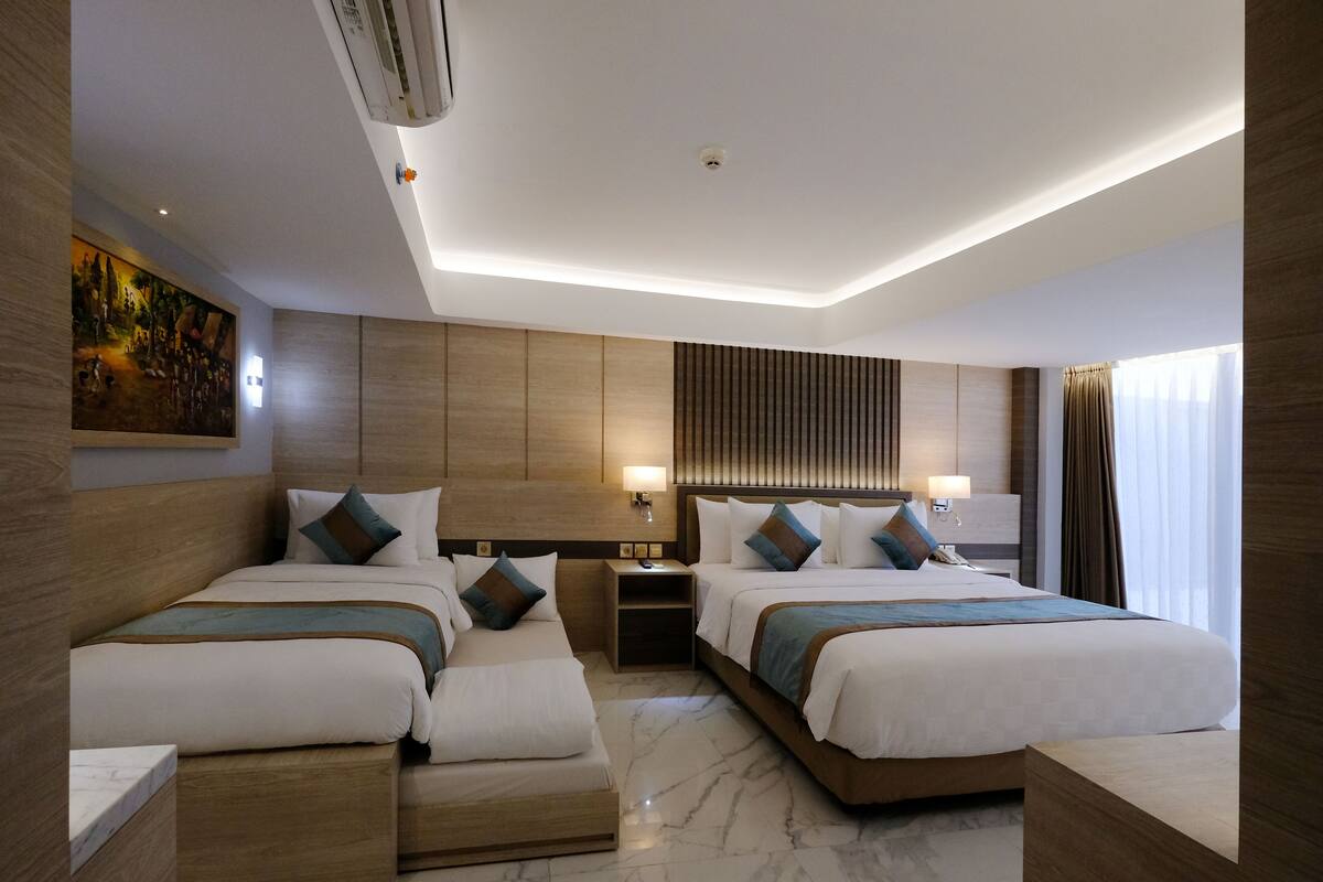 A modern hotel room with two beds, a large painting on the wall, and a ceiling with recessed lighting.
