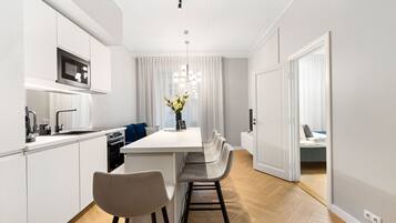 A modern kitchen with white cabinetry, a central island, and bar stools.