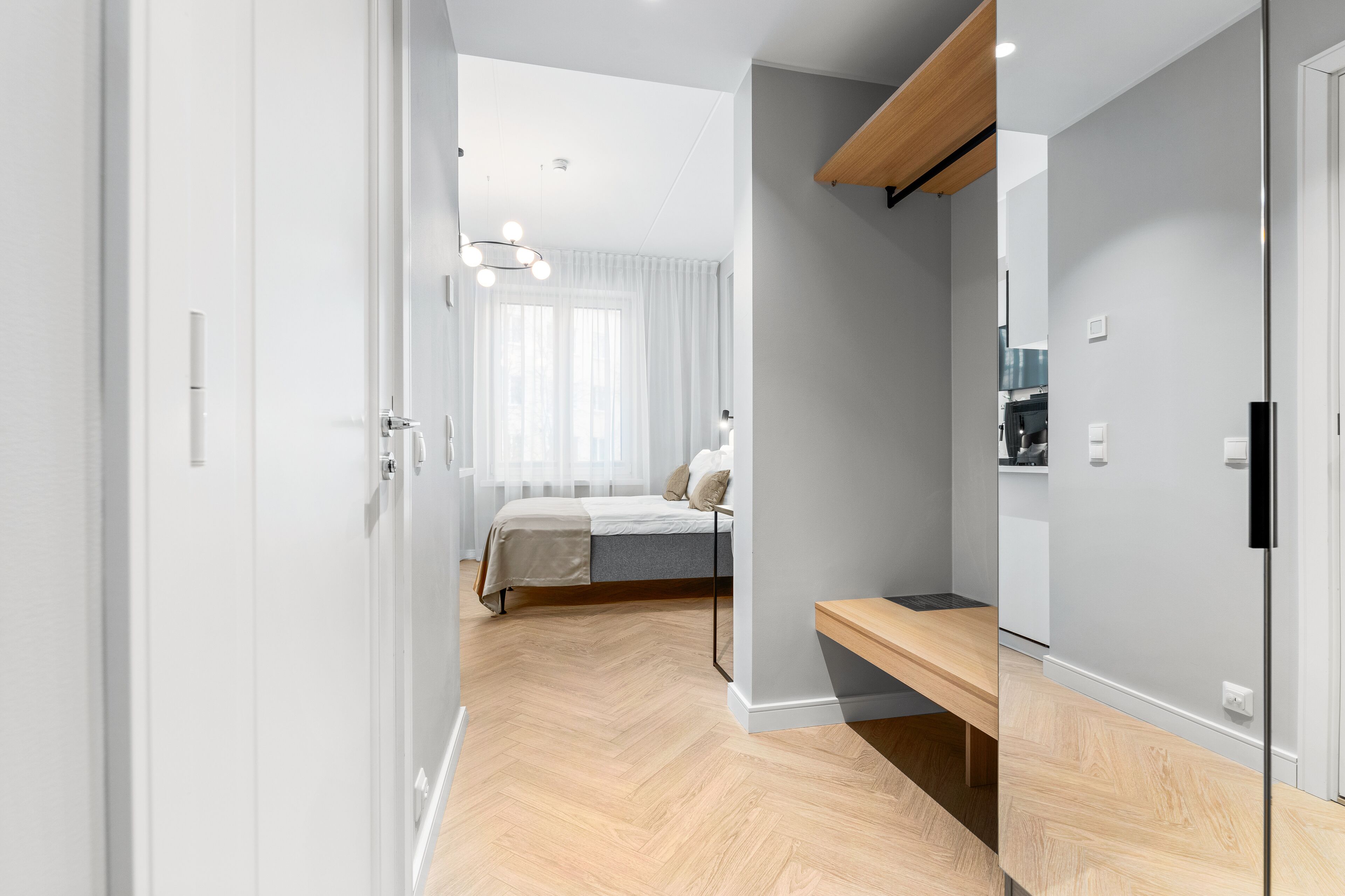 A modern bedroom with a bed, bedside table, and a large mirror.