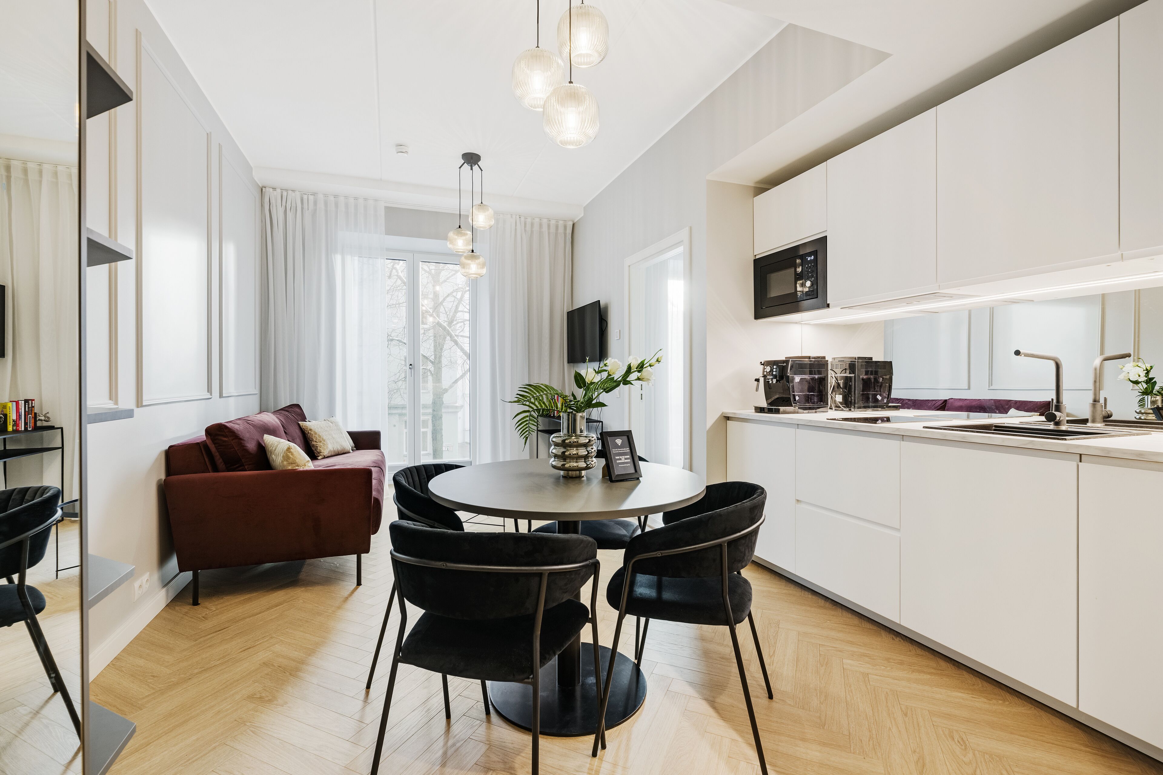 Una cocina moderna con comedor, que incluye una mesa redonda, sillas negras y un sofá rojo.