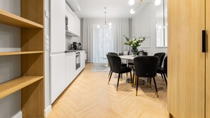 Una cocina moderna con armarios blancos, encimera de madera y un comedor con mesa y sillas.