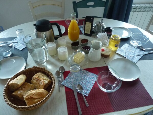 A breakfast table set with various food items, utensils, and drink containers.