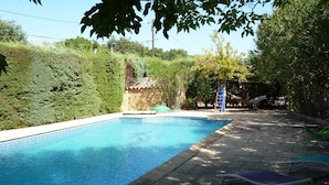 Une piscine rectangulaire dont le bord est recouvert de carreaux, entourée d’une terrasse dallée.