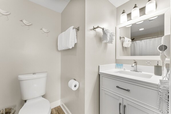 A bathroom with a toilet, towel rack, and a sink with a mirror. - Free Beach Chair Service-Shores of Panama 2207~3 bed 3 bath (Panama City Beach)
