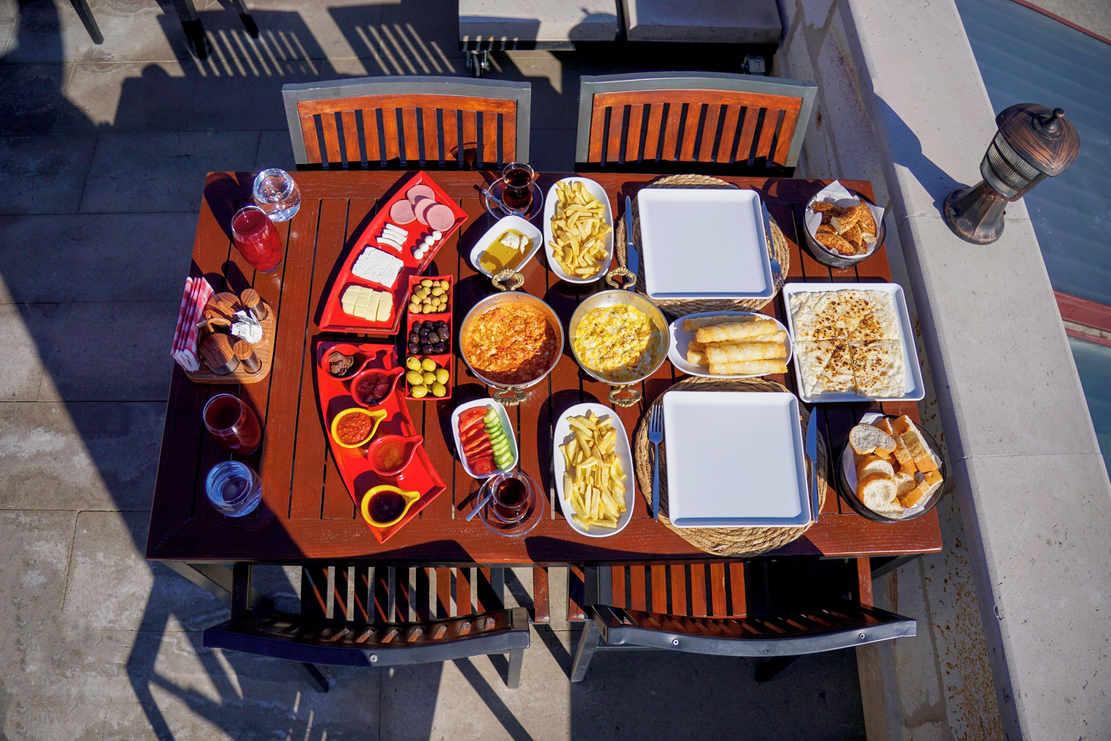 Una mesa de comedor con diversos alimentos y utensilios, rodeada de sillas.