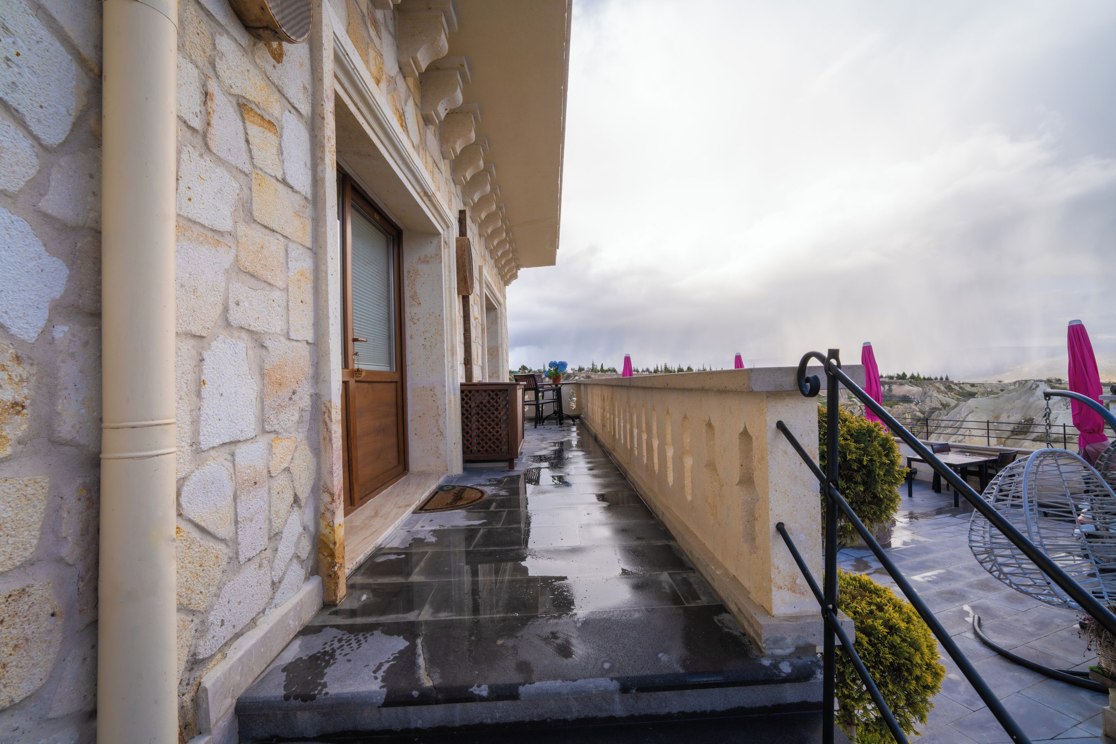 A stone building with a balcony, a metal spiral staircase, and a view of the landscape.