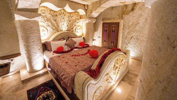Una habitación con cama, puerta y pared de piedra.