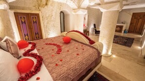 A room with a bed, a wooden door with decorative panels, a white pillar, and a patterned rug. - Cappadocia Sweet Cave (Ürgüp)