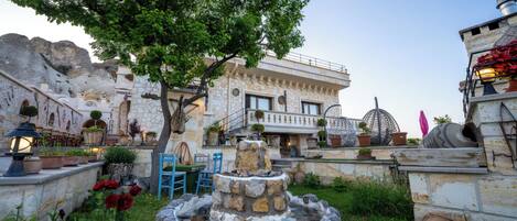 A stone building with a fountain, outdoor seating, and potted plants.