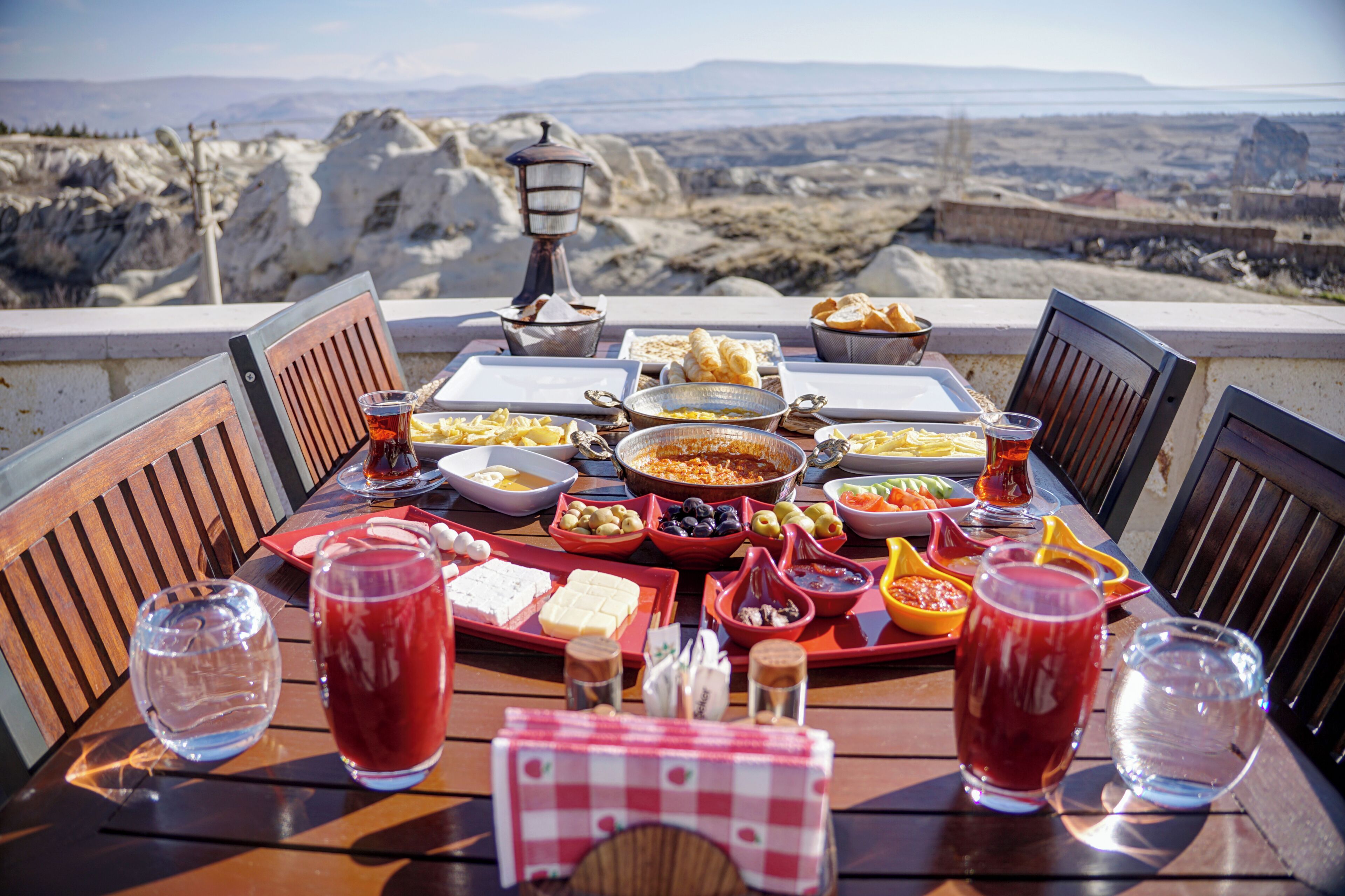 A table set with various dishes and drinks, overlooking a mountainous landscape.