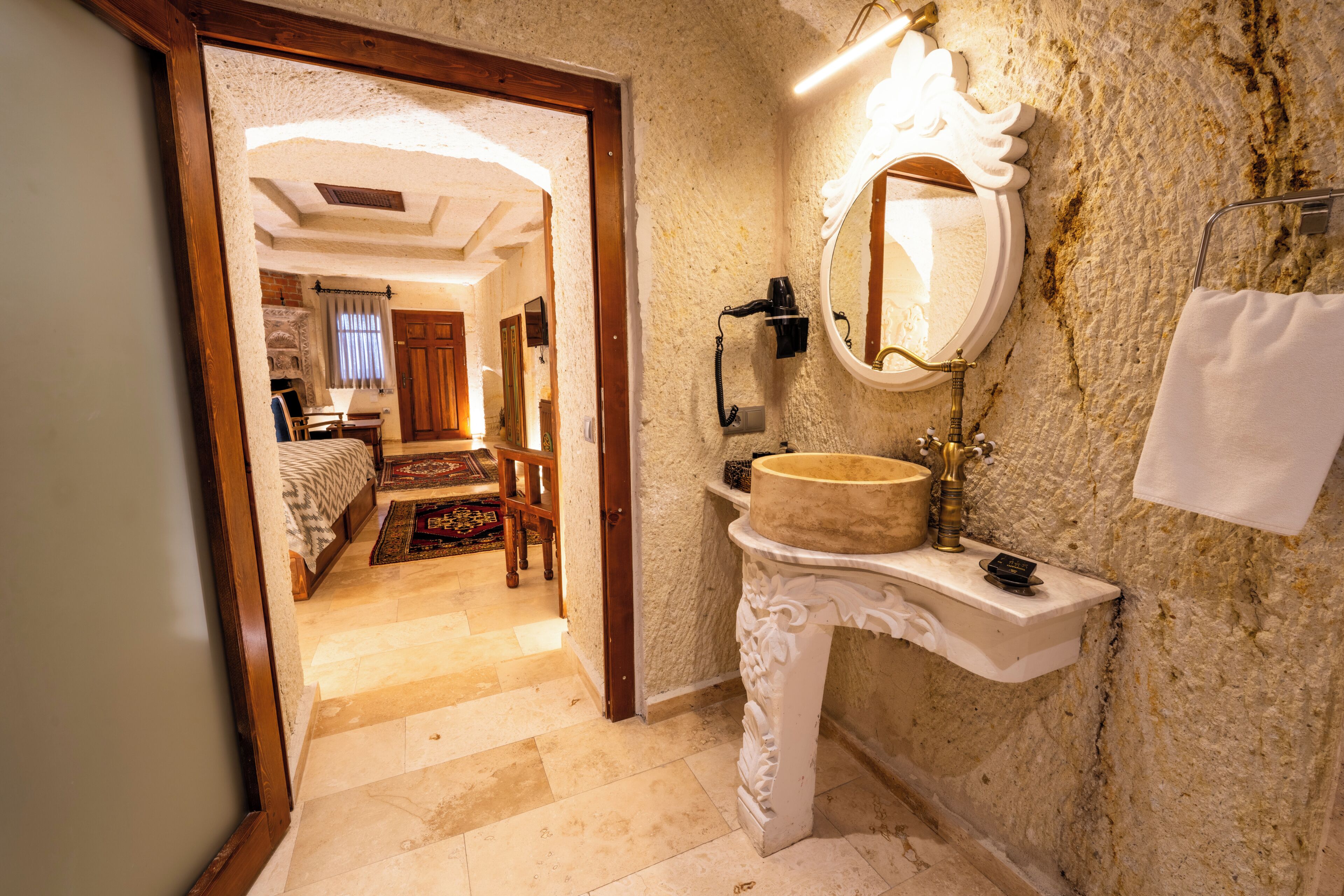 Une salle de bain avec un lavabo en pierre, un miroir et une serviette accrochée au mur.