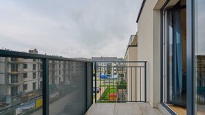 A balcony with a metal railing, a view of a street with buildings, and a clear sky. - Modern Studio on Jagodno | Balcony and Parking (Wrocław)
