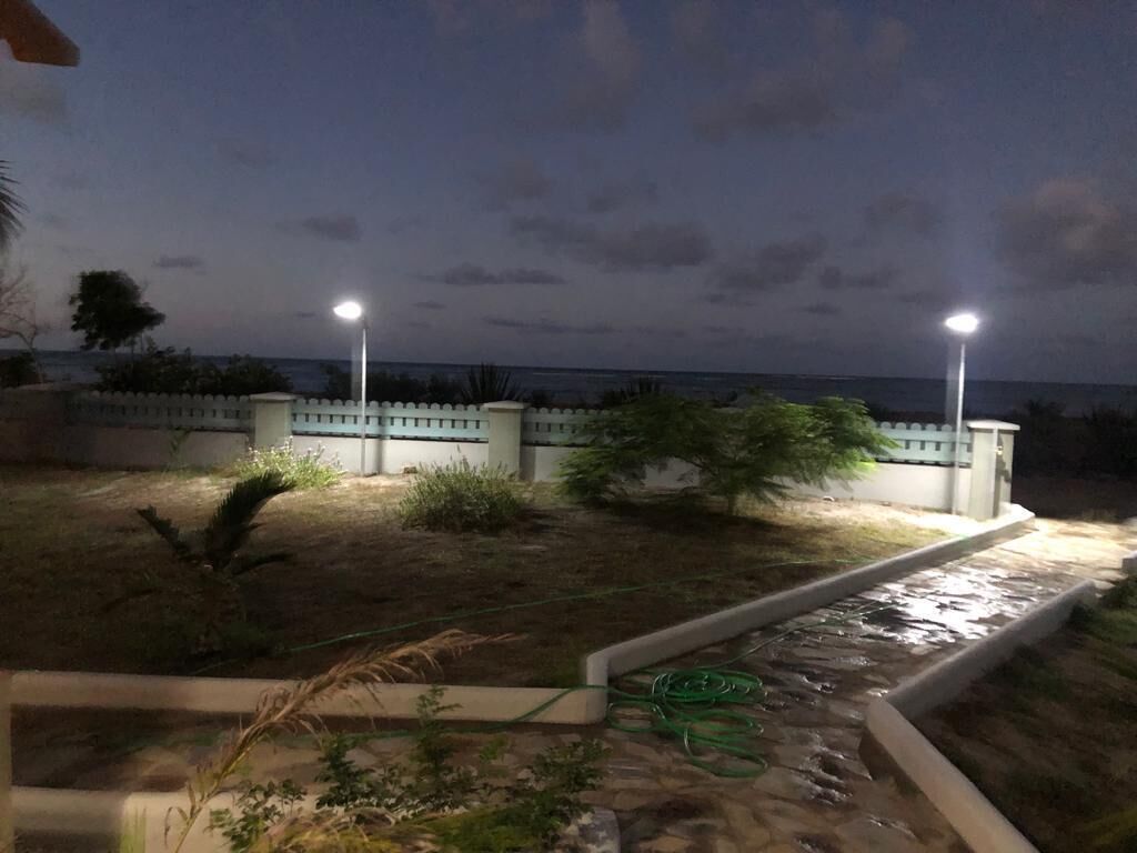 A nighttime outdoor area with a pathway, a small water feature, and two street lamps.