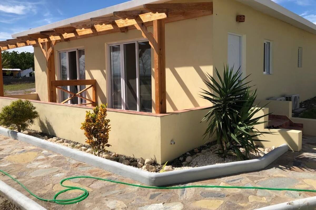 Un edificio moderno con una pérgola de madera, ventanas amplias y un patio de piedra.