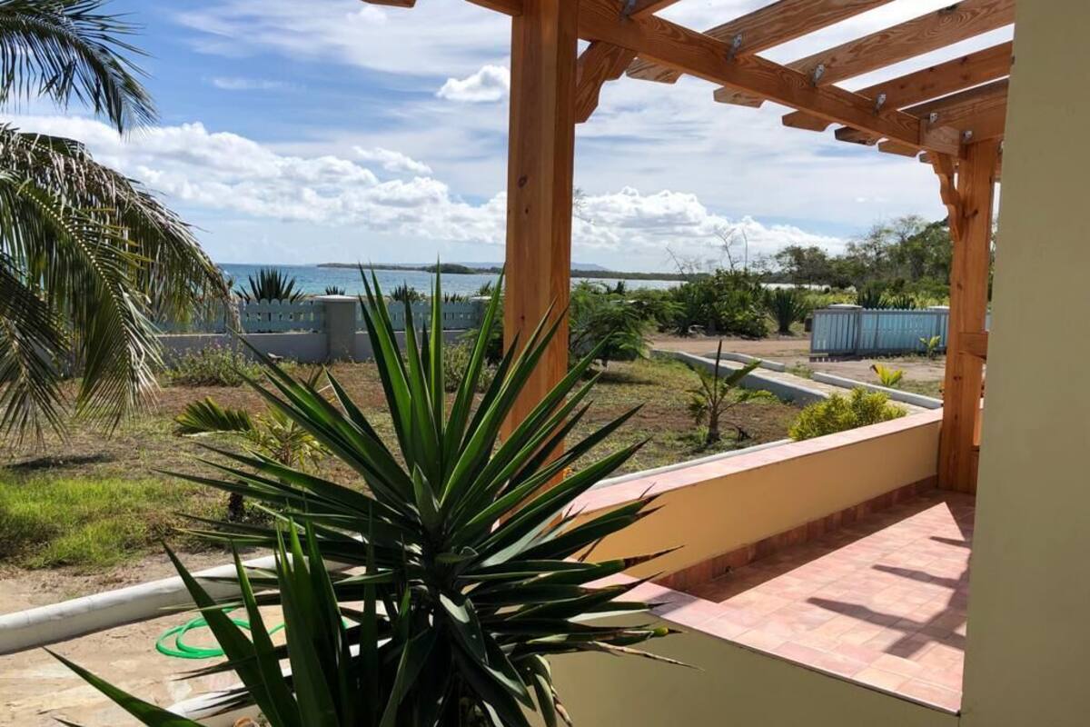 Una pérgola de madera con vistas a un paisaje costero, que incluye una masa de agua y tierra distante.