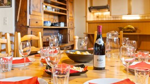Una mesa de comedor dispuesta con copas de vino, una botella de vino y un bol de fruta.