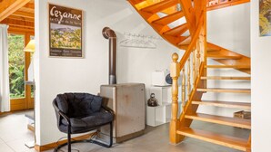 Una habitación acogedora con una escalera de madera, una silla negra, un radiador y un cartel en la pared.