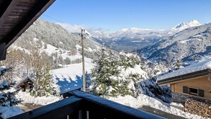 Vista de la montaña con árboles nevados y una cabaña de madera.