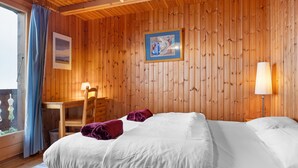 Una habitación de madera con una cama, un escritorio y una silla.
