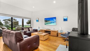 A modern living room with leather sofas, wooden coffee table, and a flat-screen TV mounted on the wall. - Castlebay - Lovely 4 bedroom home (Wimbledon Heights)