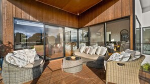 A sunlit outdoor seating area with wicker furniture and a glass enclosure. - Castlebay - Lovely 4 bedroom home (Wimbledon Heights)