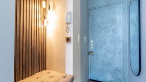 A hotel room with a wooden slat wall, a tufted bench, a white telephone, a door with a textured finish, and a mirror on the wall. - Petit Violette I Amazing 1 Bed Apt in Paris (Paris)