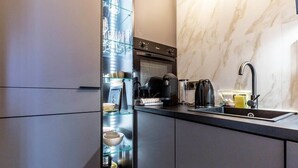 A modern kitchen with a built-in oven, a coffee machine, and a glass-fronted storage unit. - Petit Violette I Amazing 1 Bed Apt in Paris (Paris)