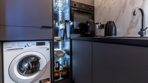 A compact kitchen with a built-in washer and dryer, a coffee maker, and a sink with a modern faucet. - Petit Violette I Amazing 1 Bed Apt in Paris (Paris)