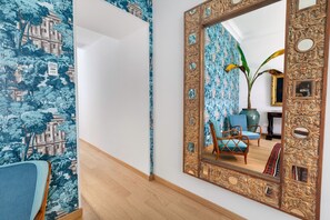 A room with a large ornate mirror reflecting a chair and a vase. The walls have a blue patterned wallpaper. - Maison Iovino Luxury Rooms (Sorrento)