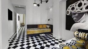 A modern room with a checkered floor, a sofa with patterned cushions, a large abstract painting, and a unique ceiling light fixture. - Maison Iovino Luxury Rooms (Sorrento)
