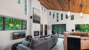 Ein modernes Wohnzimmer mit grauem Sofa, Kamin und Küchenzeile mit Spüle und Arbeitsplatte.