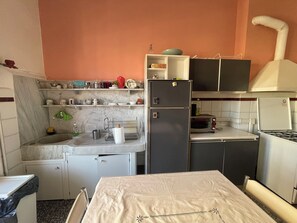 A compact kitchen with a sink, countertop, and a stove. There are cabinets above the countertop and a small refrigerator. - Gastaldi Rooms (Genoa)