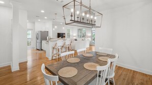 Una cocina amplia con una isla central, muebles blancos y un refrigerador de acero inoxidable.