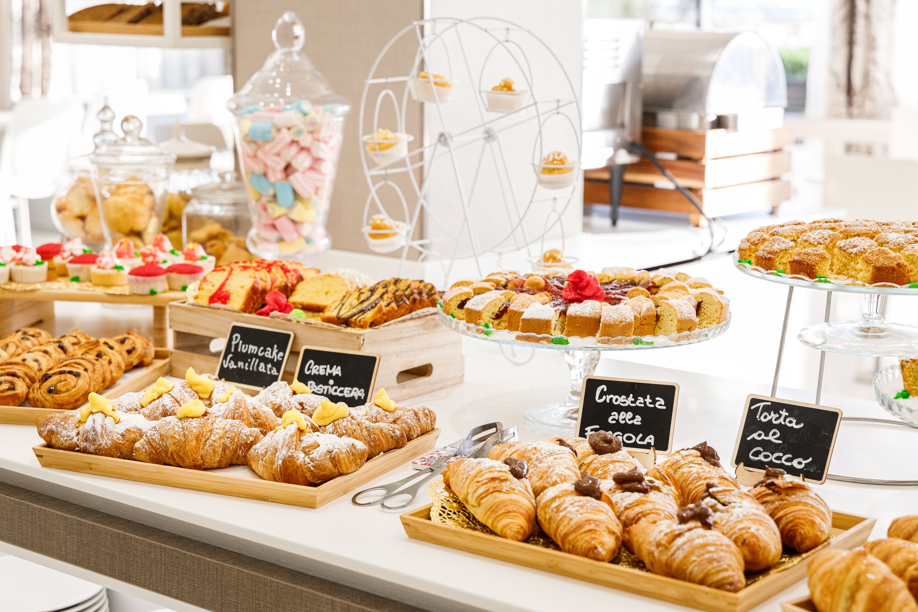 A variety of pastries and desserts displayed on a counter with labels indicating different types.