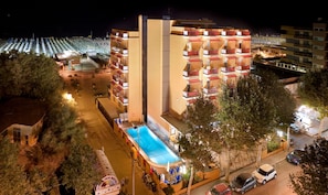 A hotel with a pool, multiple balconies, and a view of the cityscape. - Hotel Ariane (Rimini)
