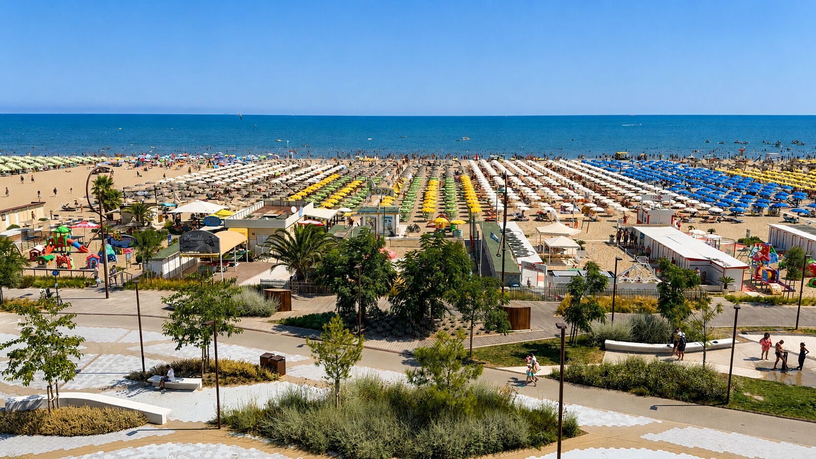 Una playa con hileras de sombrillas y sillas, un parque infantil y una vista despejada del mar.