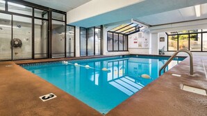 An indoor swimming pool with clear water, a diving board, and a lifeguard station.