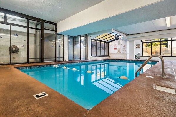 Una piscina interior con agua cristalina, un trampolín y una estación de salvavidas.