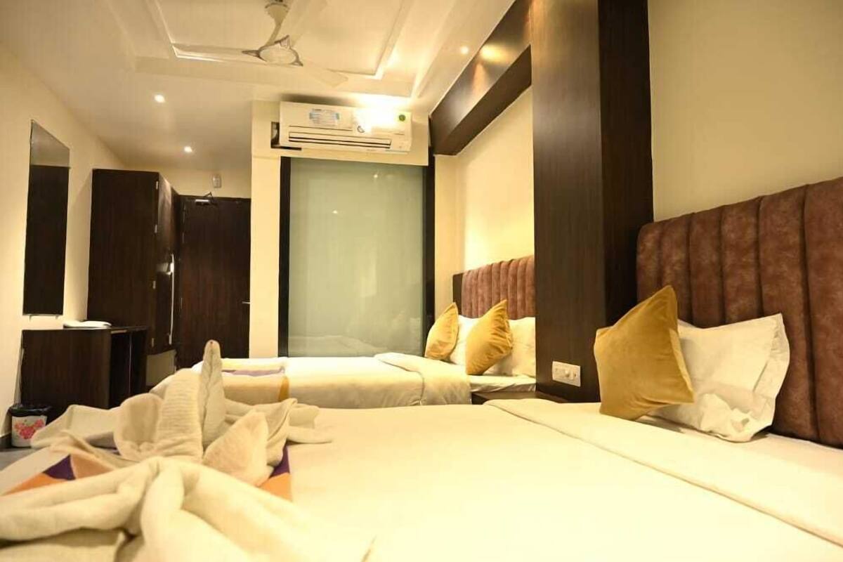 Une chambre d’hôtel avec deux lits, un grand miroir et un appareil de climatisation.