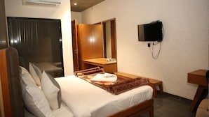 Ein Hotelzimmer mit einem Bett, einem an der Wand befestigten Fernseher, einem Spiegel und einem Holzschrank.