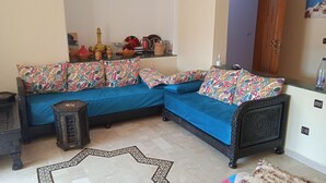 Un soggiorno con un divano blu, cuscini decorati, un tappeto da pavimento e un piccolo tavolino.