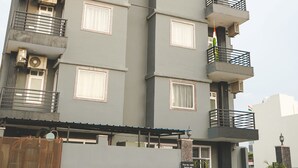 Un edificio residencial de varios pisos con balcones, unidades de aire acondicionado y plantas en macetas.