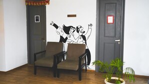 Una habitación con dos sillones, una planta en maceta y una pared con un personaje de caricatura.