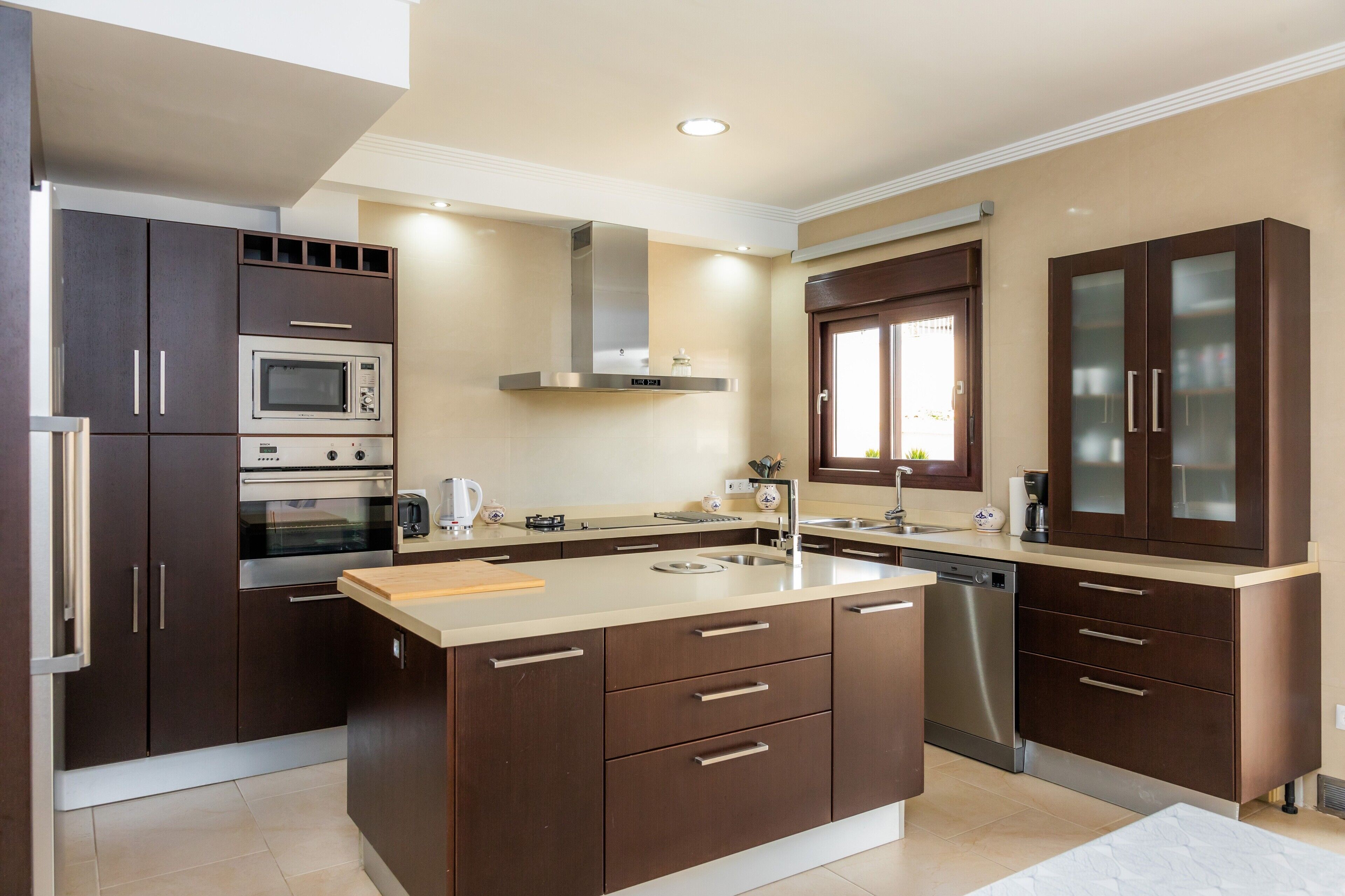 A modern kitchen with built-in appliances, a central island, and dark cabinetry.