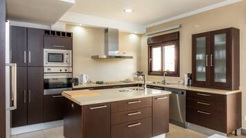 A modern kitchen with built-in appliances, a central island, and dark cabinetry.