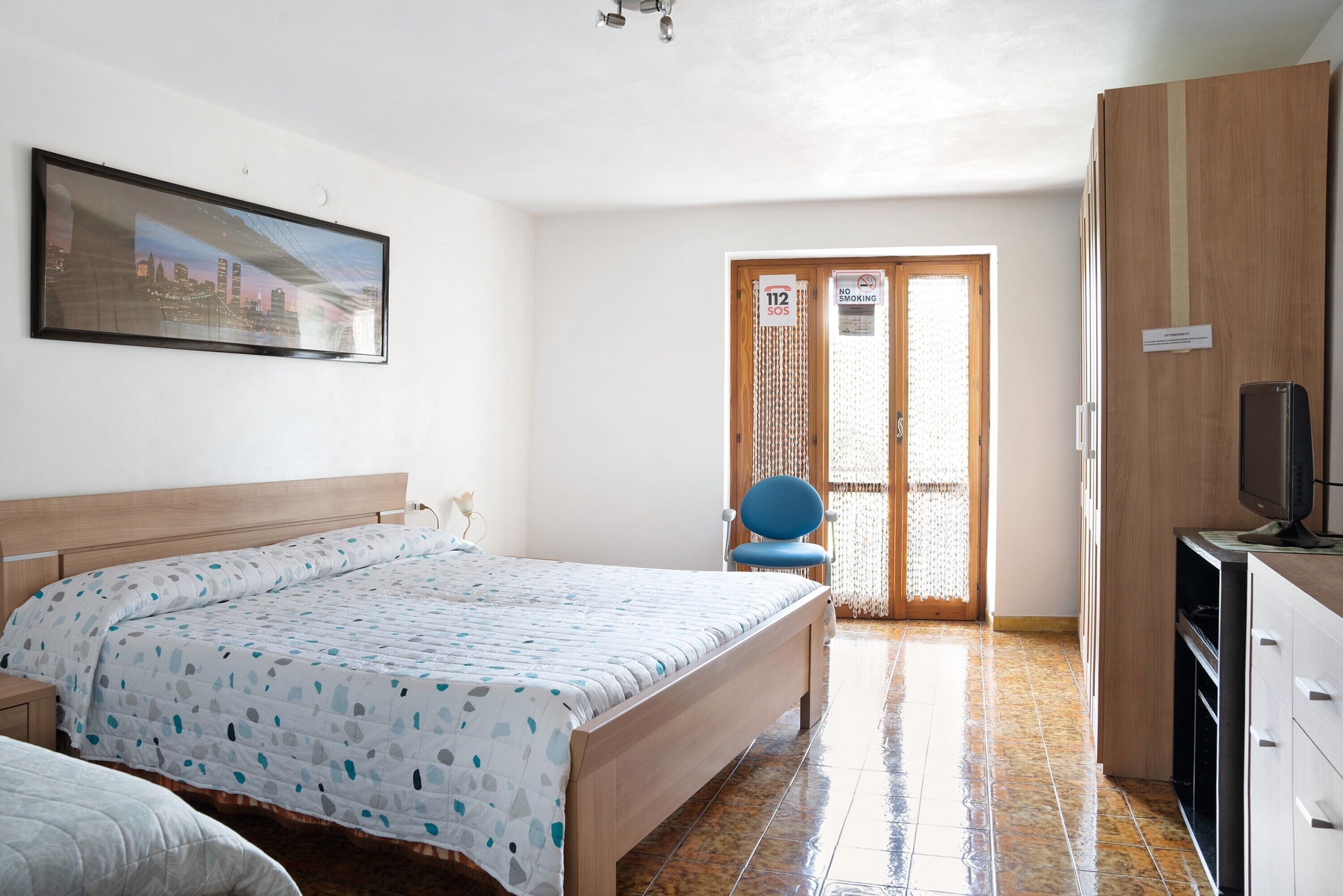 Quarto com cama, cadeira, televisão e guarda-roupa.